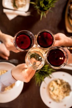 Dört el ve kırmızı şarap. Restoranda servis edilen masada kadeh kaldırma.