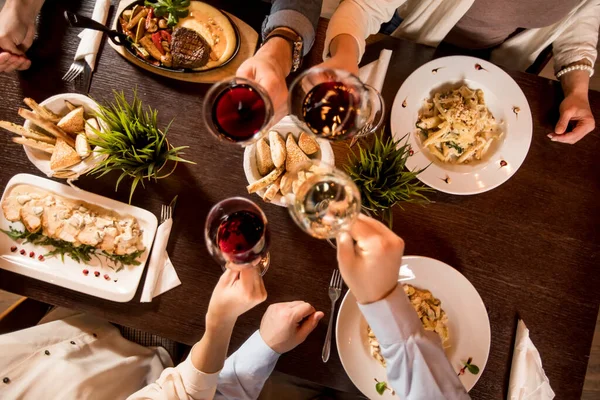 Cztery Ręce Czerwonym Winem Toasting Nad Serwowanym Stole Jedzeniem Restauracji — Zdjęcie stockowe