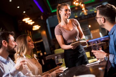 Güzel garson kadın, arkadaşlarıyla yemek servisi yapıyor.