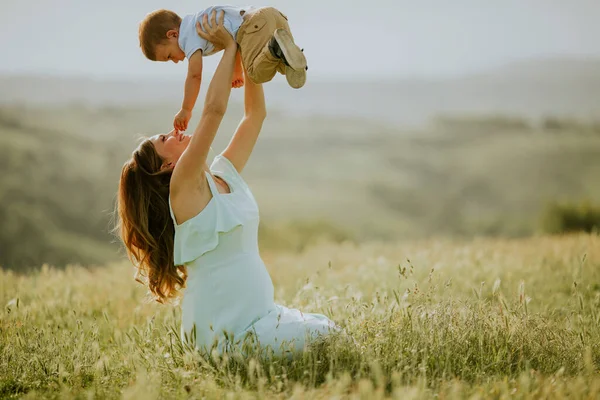 若いです妊娠中のお母さんとともに彼女の可愛いです男の子でフィールドで美しい夏の日 — ストック写真