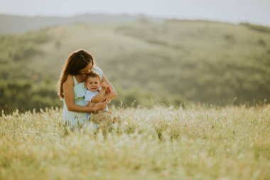 Genç hamile anne ve küçük tatlı oğlu güzel bir yaz günü tarlada.