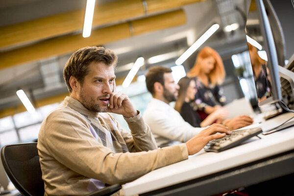 Handsome young professional businessman uses a computer for work in the modern office