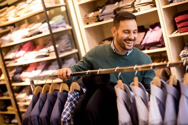 Handsome young man buying shirt in the store