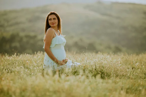 若いです妊娠中の女性で白いドレスで夏のフィールド — ストック写真