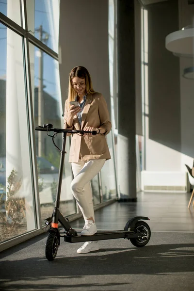 Jolie Jeune Femme Debout Près Fenêtre Bureau Avec Scooter Électrique — Photo