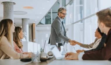 Olgun iş adamı, ofiste yeni bir proje üzerinde çalışırken bir grup etnik çeşitliliğe sahip iş adamına stratejiyi anlatıyor.