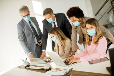 Grup iş adamlarının ofiste bir toplantısı var ve Corona virüsünden korunmak için maske takıyorlar.