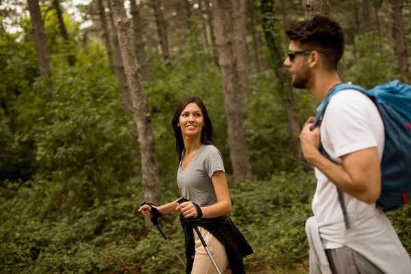 一对背着背包在森林里散步的年轻夫妇笑着 — 图库照片
