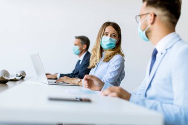 İş adamlarının bir toplantısı var ve ofiste çalışıyorlar. Korona virüsünden korunmak için maske takıyorlar.