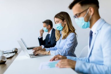 İş adamlarının bir toplantısı var ve ofiste çalışıyorlar. Korona virüsünden korunmak için maske takıyorlar.