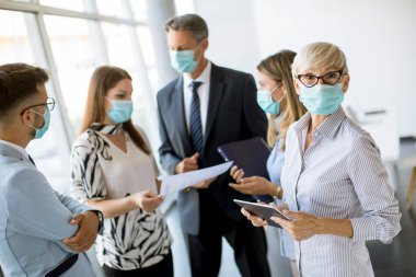 İş ortakları ofiste maske takarken ve virüs koruması takarken iş sonuçlarını inceliyor.