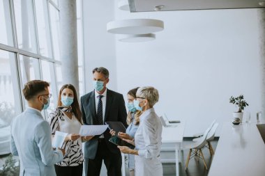 İş ortakları ofiste maske takarken ve virüs koruması takarken iş sonuçlarını inceliyor.