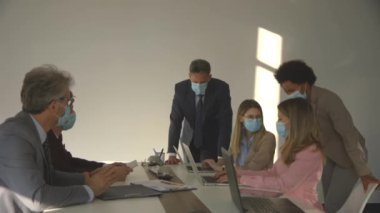 İş adamlarının bir toplantısı var ve ofiste çalışıyorlar. Korona virüsünden korunmak için maske takıyorlar.