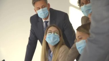 İş adamlarının bir toplantısı var ve ofiste çalışıyorlar. Korona virüsünden korunmak için maske takıyorlar.