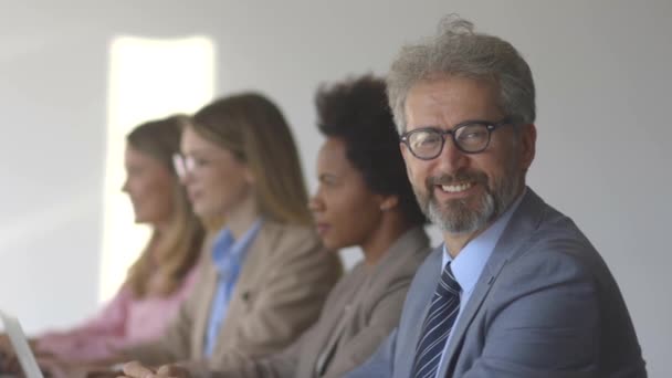 Gruppe multiethnischer Geschäftsleute arbeitet im modernen Büro an einem neuen Projekt, während ihr Anführer in die Kamera schaut — Stockvideo