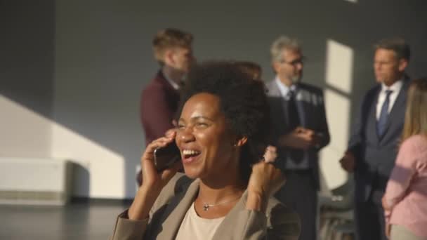 Afroamerykańska bizneswoman odbiera wspaniałe wieści przez telefon komórkowy w biurze — Wideo stockowe