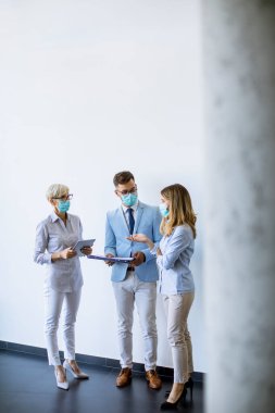 İş ortakları ofiste maske takarken ve virüs koruması takarken iş sonuçlarını inceliyor.