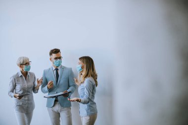 İş ortakları ofiste maske takarken ve virüs koruması takarken iş sonuçlarını inceliyor.