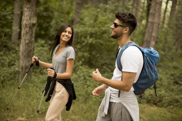 一对背着背包在森林里散步的年轻夫妇笑着 — 图库照片