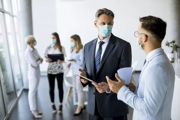 Office workers have a meeting in the office with face masks as a protection from coronavirus