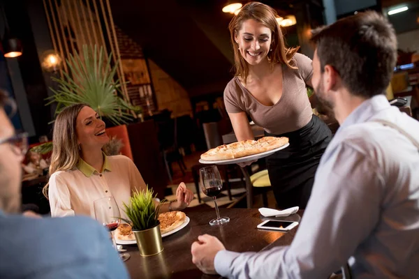 可愛いウエイター女性はレストランで食べ物と友人のグループにサービスを提供 — ストック写真
