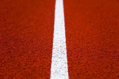 Closeup of the white line on red stadium running track clipart