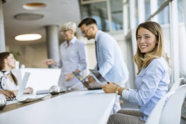 Güzel genç kadın ve grup iş adamları ofiste toplanıp çalışıyorlar.