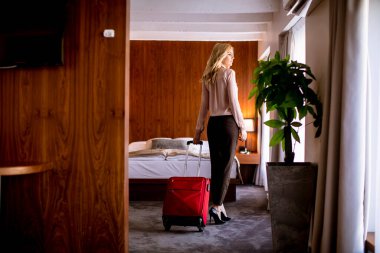 Güzel sarışın iş kadını kırmızı bavuluyla otel odasına geliyor.