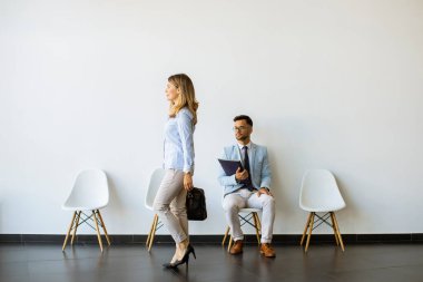 Bavullu bir iş kadını, röportajdan önce elinde bir dosyayla bekleme odasında oturan genç bir adamın yanından geçiyor.