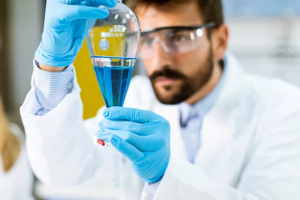 Laboratuvardaki Ayrıştırıcı Hunide Mavi Sıvıyla Çalışan Bir Araştırmacı — Stok fotoğraf