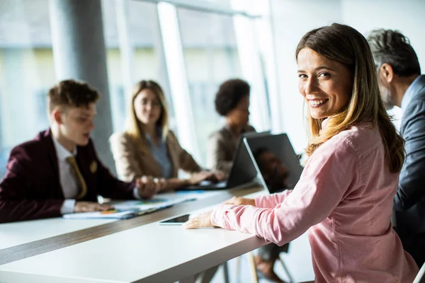 近代的なオフィスで成功したビジネスミーティング中に笑みを浮かべてかなり若い女性 — ストック写真