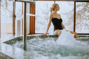 Güzel genç bir bayan banyoda oturmuş dinleniyor.