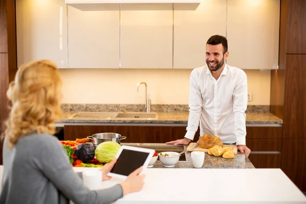 Mujer Joven Usando Tableta Mesa Cocina Mientras Hombre Prepara Comida — Foto de Stock