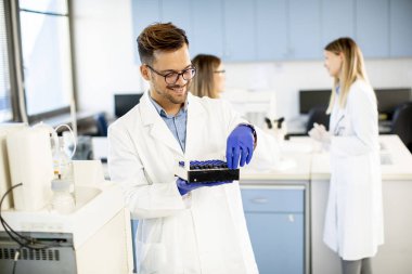 Laboratuvarda duran ve sıvı örneklerini analiz eden koruyucu iş giyimi araştırmacısı.