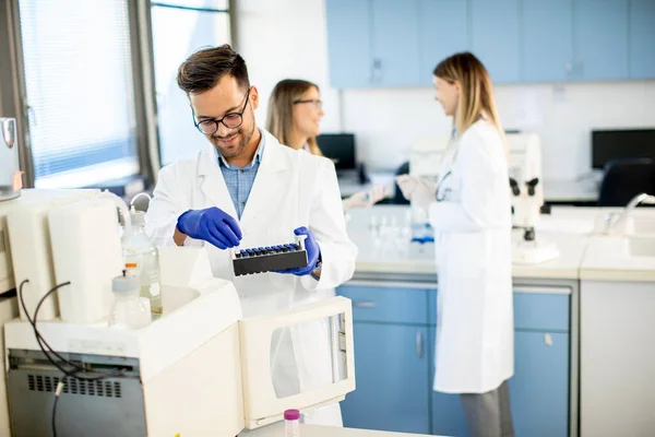 研究室に立って液体試料を分析する保護作業服のハンサムな研究者 — ストック写真