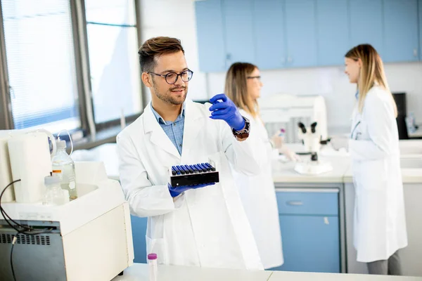 研究室に立って液体試料を分析する保護作業服のハンサムな研究者 — ストック写真