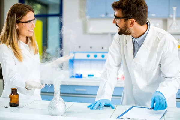 Young researchers doing experiment with smoke on a table of a chemical laboratory