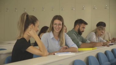 Sınıf arası sırasında üniversite sınıfında oturan genç öğrenciler