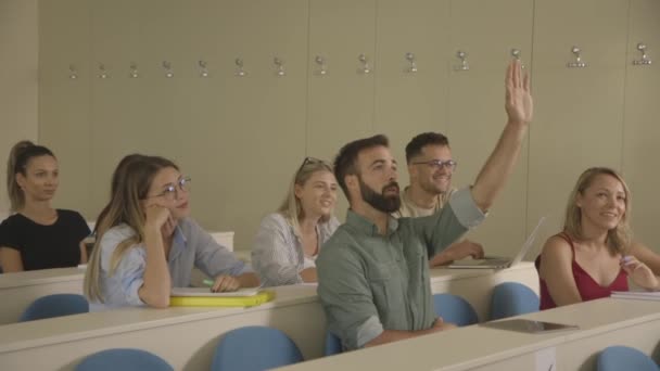 Jóvenes estudiantes sentados en el aula universitaria — Vídeos de Stock