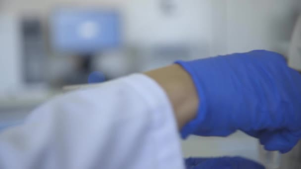 Mão na luva protetora segurando tubo de teste no laboratório — Vídeo de Stock