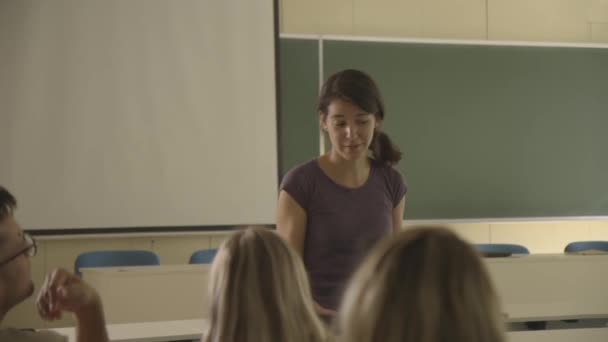 Jonge vrouwelijke docent onderwijsgroep van jonge studenten in de klas van de universiteit — Stockvideo