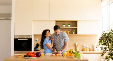 Bir çift, yemek hazırlarken şık mutfaklarında büyüleyici bir anı paylaşıyor. Taze sebzeler tezgaha yayılır ve kahkahalar havayı doldurur..