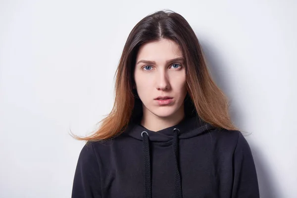 Calm woman standing by white wall looking to side — Stock Photo, Image