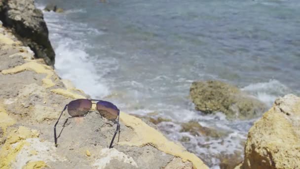 Okulary przeciwsłoneczne leżące na ogrodzenie z kamienia — Wideo stockowe