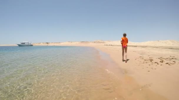 Chica en traje de baño huyendo en la playa del mar en el desierto — Vídeos de Stock