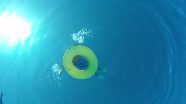 Девушка, плавающая на надувном кольце в бассейне, вид из-под воды — стоковое видео