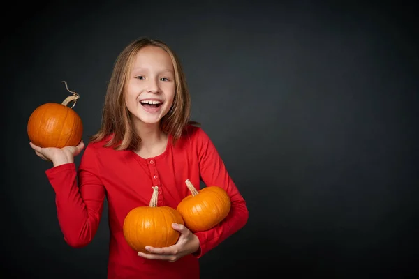 Happy girl holding the ripe orange pumpkins — Stock Photo, Image