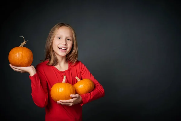 Happy girl holding the ripe orange pumpkins — Stock Photo, Image