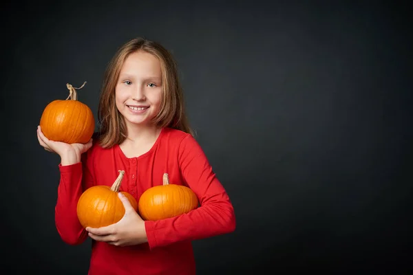 Chica feliz sosteniendo las calabazas naranjas maduras —  Fotos de Stock