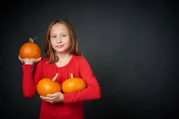 Chica feliz sosteniendo las calabazas naranjas maduras —  Fotos de Stock